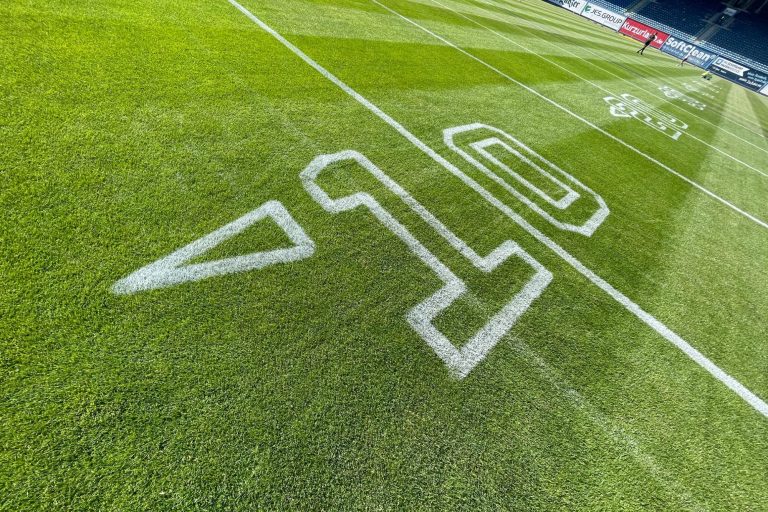 10 Yard Linie mit Zahl und Richtungspfeil auf dem Footballfeld im Stadion